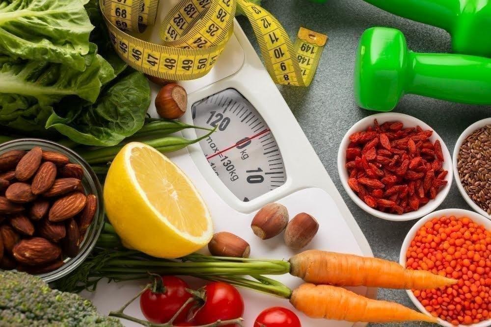 A comprehensive display of healthy foods, green dumbbells, a measuring tape, and a scale, representing the core pillars of metabolic health and weight loss.