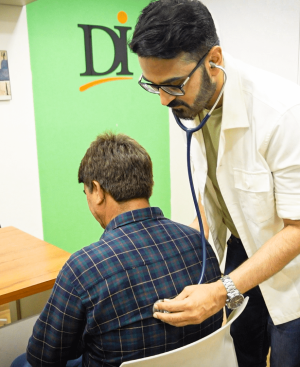 Dr. Ikram using a stethoscope to examine a patient's back at a medical weight loss clinic Karachi, ensuring medical safety.