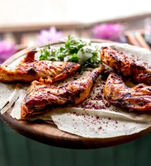 Freshly grilled chicken tikka on a wooden tray with fresh herbs, an ideal choice among high-protein Pakistani foods for fat loss.