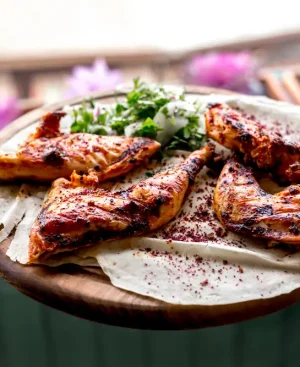 Freshly grilled chicken tikka on a wooden tray with fresh herbs, an ideal choice among high-protein Pakistani foods for fat loss.