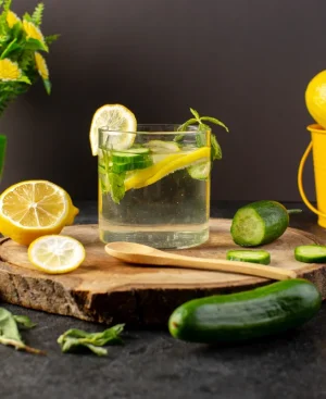 A glass of fresh lemon, cucumber, and mint infused detox water on a wooden platter, recommended as part of a uric acid diet plan in Pakistan.