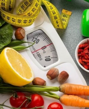 A comprehensive display of healthy foods, green dumbbells, a measuring tape, and a scale, representing the core pillars of metabolic health and weight loss.