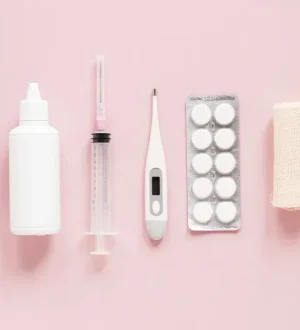 Flat lay of medical tablets, a digital thermometer, and clinical supplies on a soft pink background representing safe PCOS supplement options.