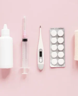 Flat lay of medical tablets, a digital thermometer, and clinical supplies on a soft pink background representing safe PCOS supplement options.